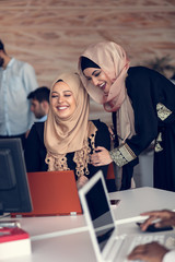 Two woman with hijab working on laptop in office.