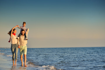 happy young family have fun on beach run and jump at sunset