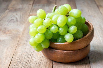 Bunch of green ripe grapes in wooden bowl, copy space