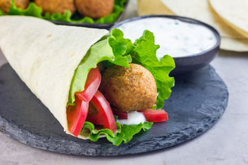 Chickpea falafel balls with vegetables and white sauce, roll sandwich preparation, horizontal, copy...