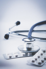 Bottles of pills and a medical stethoscope on white background