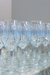 Lot of clear empty wine glasses on granite stone table and grey background. Selective focus