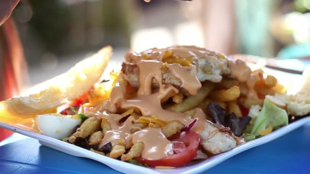 Woman eating a unhealthy salad in exotic tropical cafe