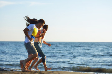 Naklejka premium Group of friends having fun walking down the beach at sunset
