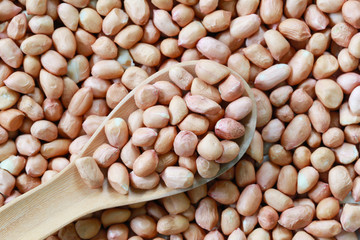 Peanut in wooden spoon on bean background.