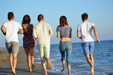 Group of friends having fun walking down the beach at sunset