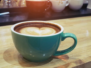 a cup of coffee on wood  table . Simple breakfast or coffee break in morning/ selective focus.blank seating  indoor in urban cafe. color filter effect