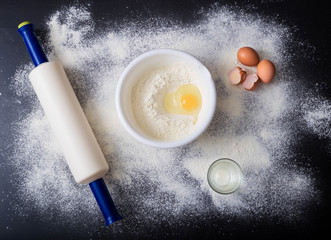 Broken eggs in a bowl, flour and various tools. The recipe for the preparation of the dough. Above...