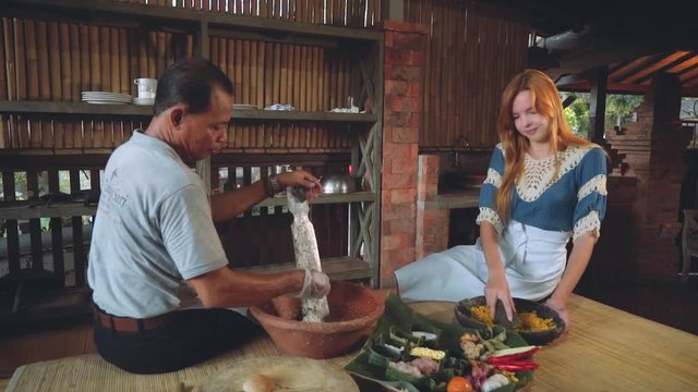 Cooking class, balinese man cooking with caucasian woman, slow motion