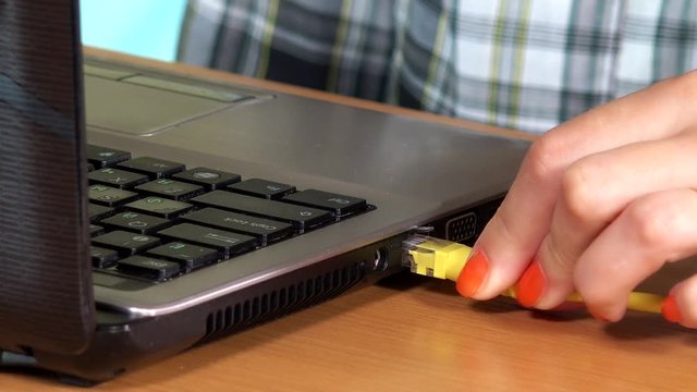 Secretary woman hand connect internet lan cable to laptop computer. Closeup