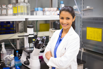 Closeup portrait, young smiling scientist in white lab coat standing by microscope. Isolated lab...