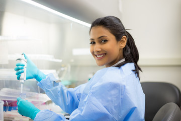 Closeup portrait, scientist pipetting from 50 mL conical tube with blue liquid solution, performing laboratory experiments, isolated lab . Forensics, genetics, microbiology, biochemistry