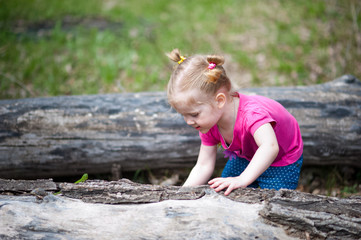 A little girl in a pink T-shirt in the summer for a walk in the clearing. The girl yawns, walks, collects flowers, looks at the lizard.