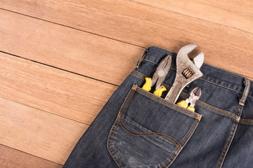 Several tools in a denim workers pocket  on wood planks