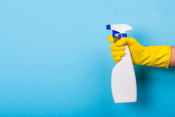 hand in a yellow glove holds a spray of cleaning fluid. copy space