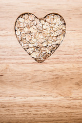 Oat cereal heart shaped on wooden surface.