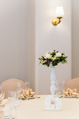 Professionally composed bridal bouquet from roses and orchids flowers of different colors and other floristic materials in white pot on table.