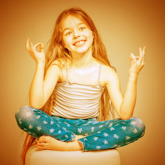Girl with long hair and in jeans meditating in a lotus pose. Toned