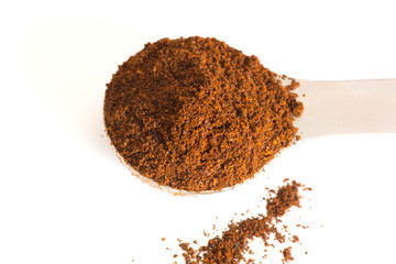 Kaffeepulver und ein Kaffeelöffel auf weisem Hintergrund