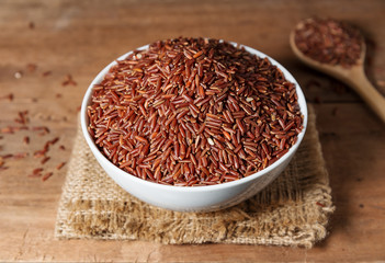 Rice berry in white bowl on wooden background