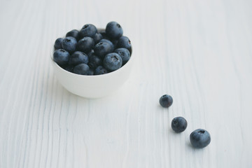 Blueberries in a white bowl on a wooden background