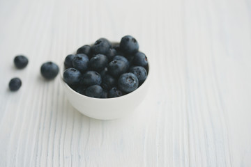 Blueberries in a white bowl on a wooden background