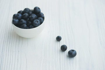 Blueberries in a white bowl on a wooden background