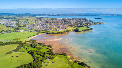 Aerial view on sunny beach with residential suburb on the background. Auckland, New Zealand.