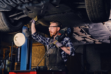 Obraz na płótnie Canvas Mechanic holds angle grinder on a shoulder.