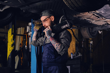Mechanic holds angle grinder on a shoulder.