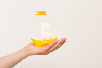 Paper boat in hand on white background