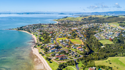 Aerial view on sunny beach with residential suburb on the background. Auckland, New Zealand.
