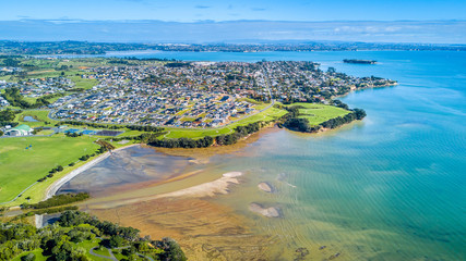 Aerial view on sunny beach with residential suburb on the background. Auckland, New Zealand.