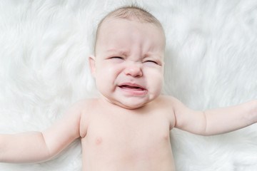 Cute baby crying on a white fur