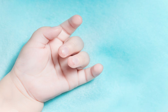 Hand of a baby with a goat gesture on a blue background