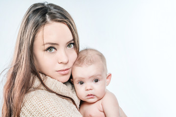 Woman in a sweater is holding a baby on a white background