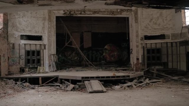 CLOSE UP: Colorful graffiti adorn decaying theatre stage in abandoned once majestic City Methodist Church, Gary, Indiana. Crumbling music room with weathered wooden floor in old collapsing building