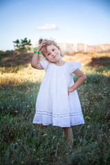 Full body portrait of a cute little girl in white dress at the beach