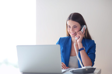 Portrait of a young woman on phone in front of a laptop computer