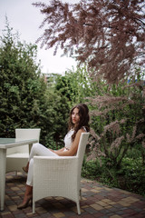 Beautiful brunette drinking coffee on summer terrace, outdoor coffee shop, cafe, street cafe