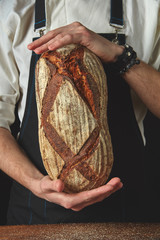 Hands of man holding oval bread