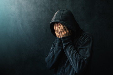 Desperate man in hooded jacket is crying