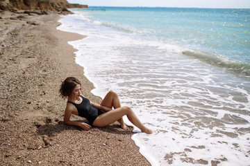 High fashion look.glamor beautiful sexy stylish brunette young female model with bright make-up, with perfect sunbathing clean skin in a black swimsuit on the beach in fashion style