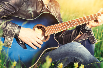 Obraz na płótnie Canvas Play the acoustic guitar in a summer meadow in the sun