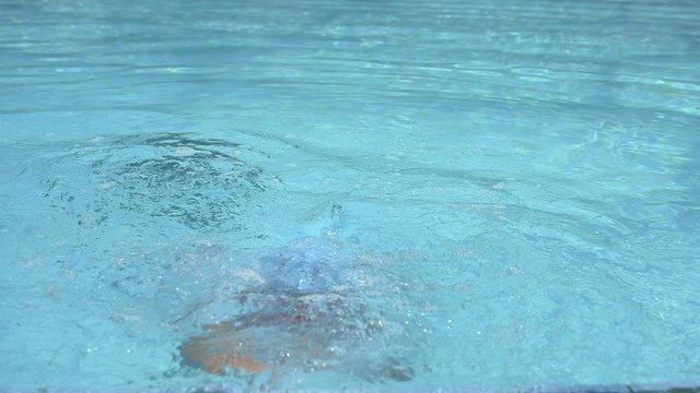 Slow motion of little girl diving into water in swimming pool. Concept of sport and leisure.