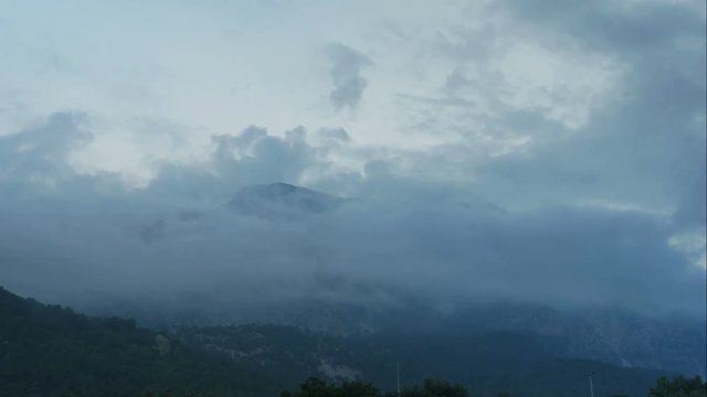 Timelapse clouds fly near the top of the mountains
