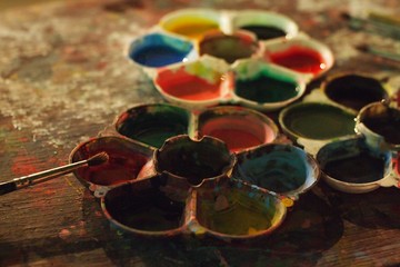 colorful dirty artistic table with color palettes and paint brushes SELECTIVE FOCUS