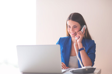 Portrait of a young woman on phone in front of a laptop computer