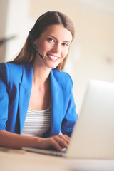 Portrait of beautiful business woman working at her desk with headset and laptop.
