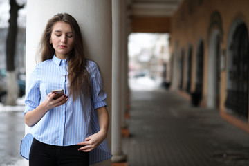 Fototapeta premium Young beautiful girl on a walk near building with a column